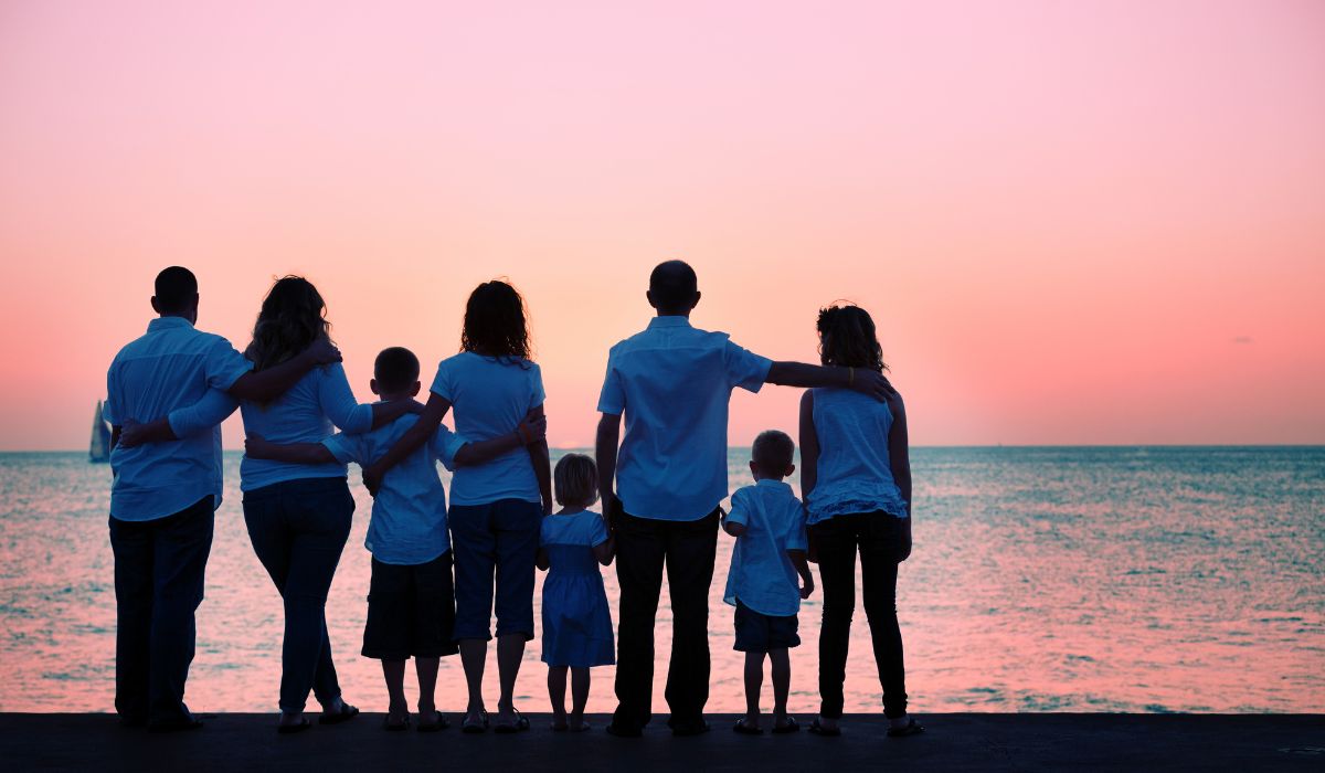 Multigenerational family silhouetted together watching a sunset over the sea, a family holiday planned by World Class Adventures