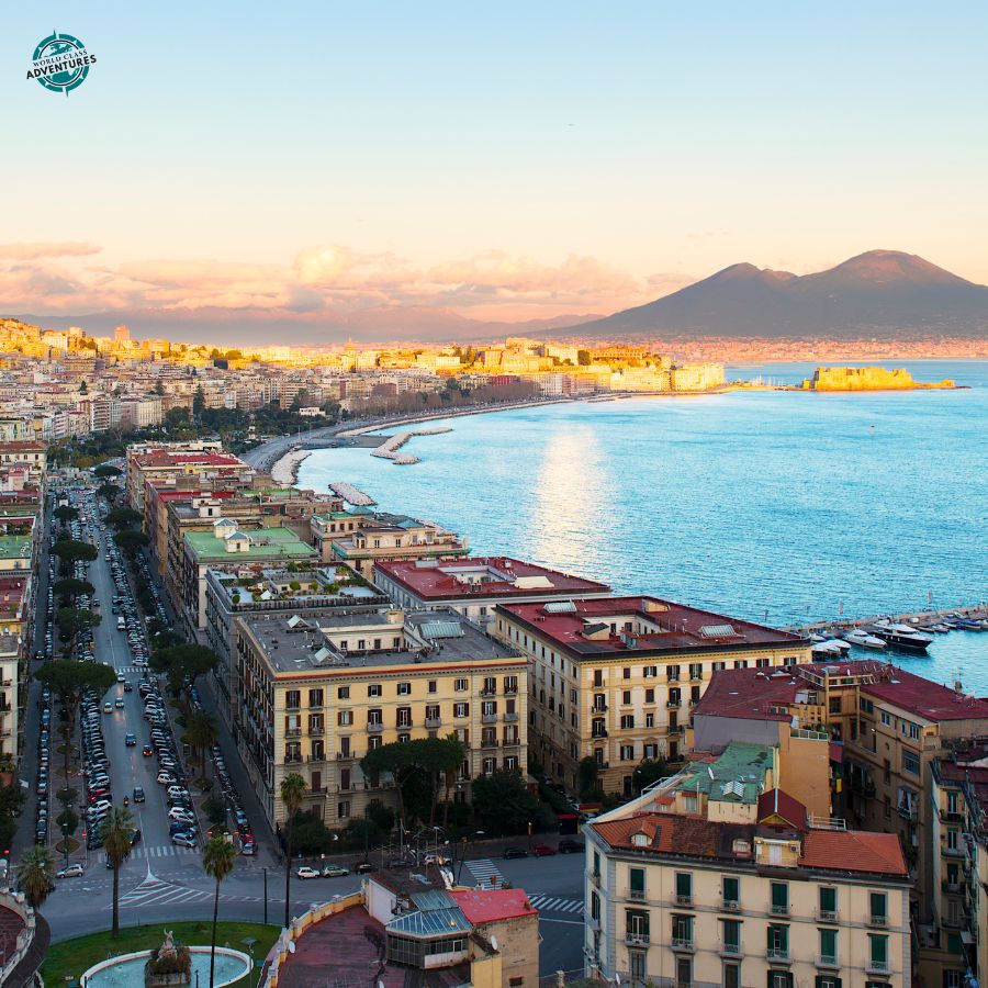 Panoramic view of Naples at sunset with the bay, seafront boulevard and Vesuvius visible across the water