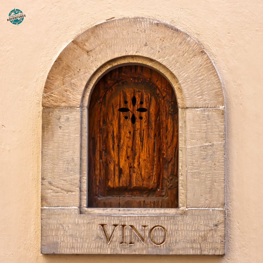 A wine window set into a stone wall in Florence with the word Vino carved below